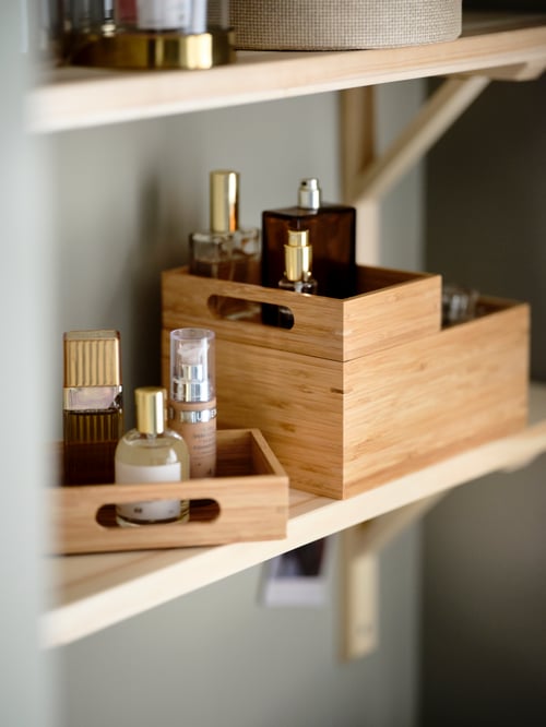 Beauty accessories on wall-mounted natural-wood shelves, many of them organised in a DRAGAN bamboo three-box set.