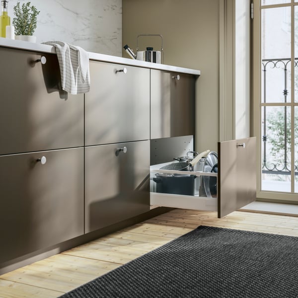Een bruine HAVSTORP keuken met een openstaande lade met daarin HEMLAGAD pannen.