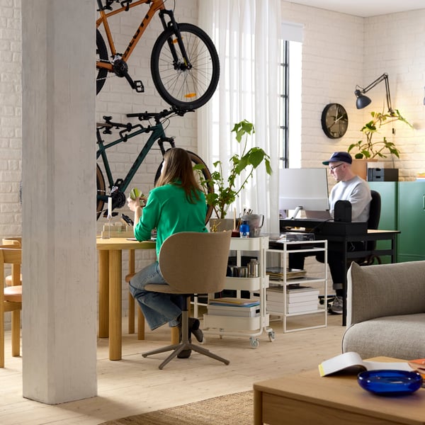 An apartment with a work-from-home setup. One person sits behind a STOCKHOLM table and the other at a MULLSJÖ desk.