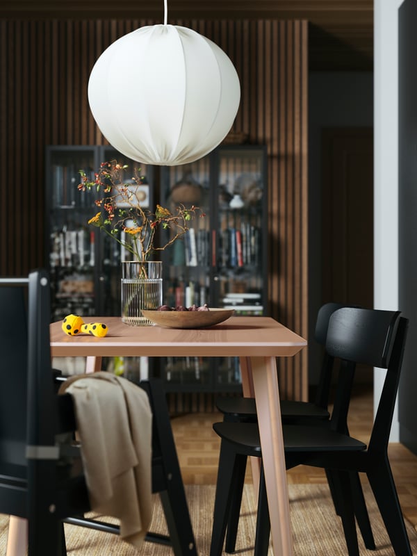 A room with a LISABO dining table in oak veneer and LISABO chairs in black, a REGNSKUR/SUNNEBY pendant lamp in white above.