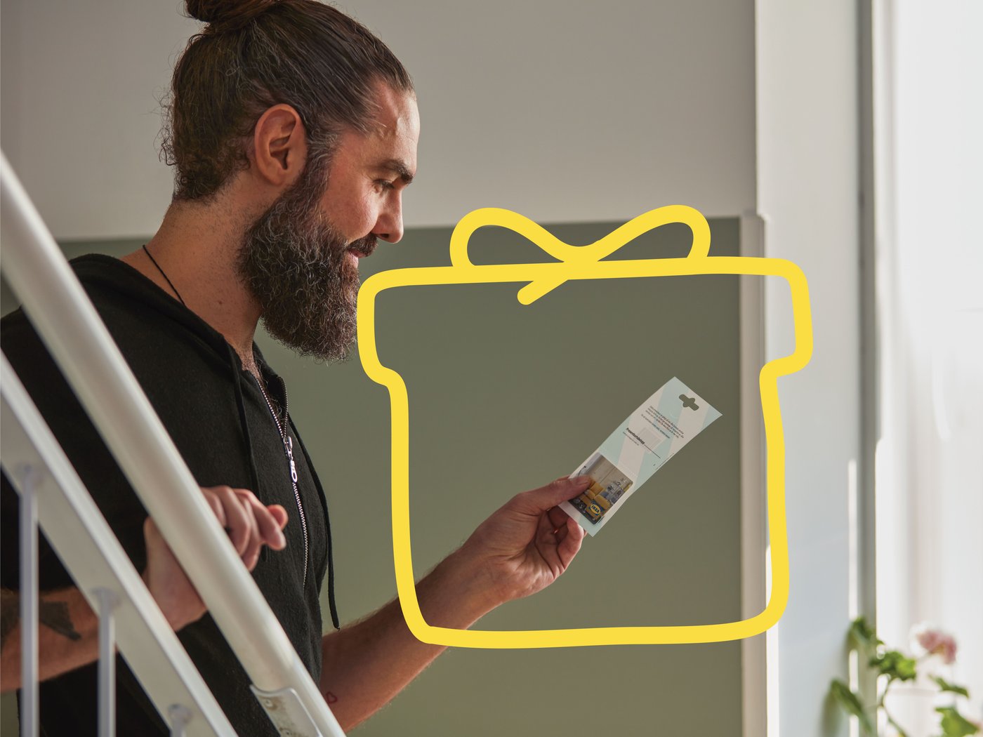 Man holding IKEA gift card smiling.