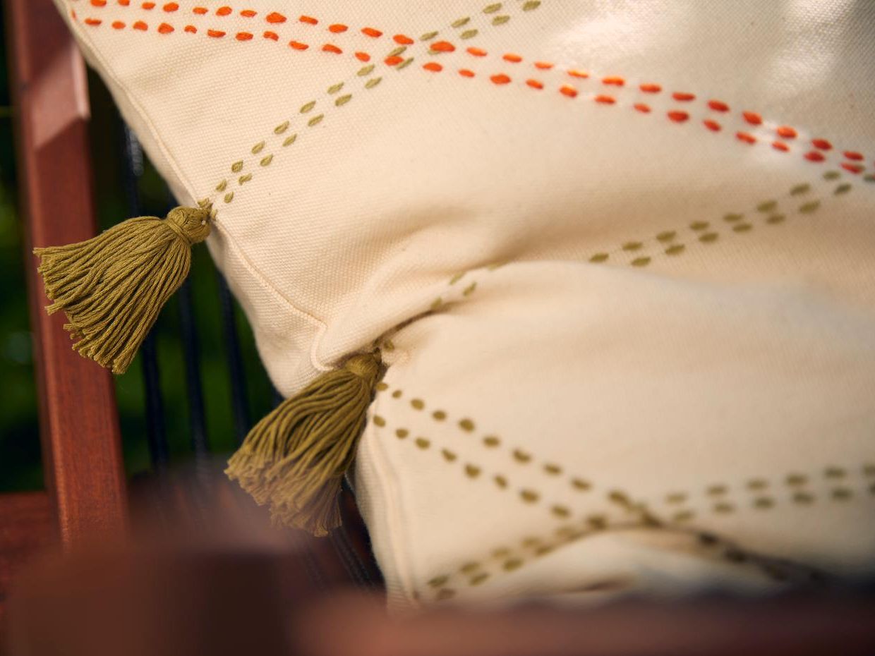 Hellbeiges Kissen mit Streifen und Quasten