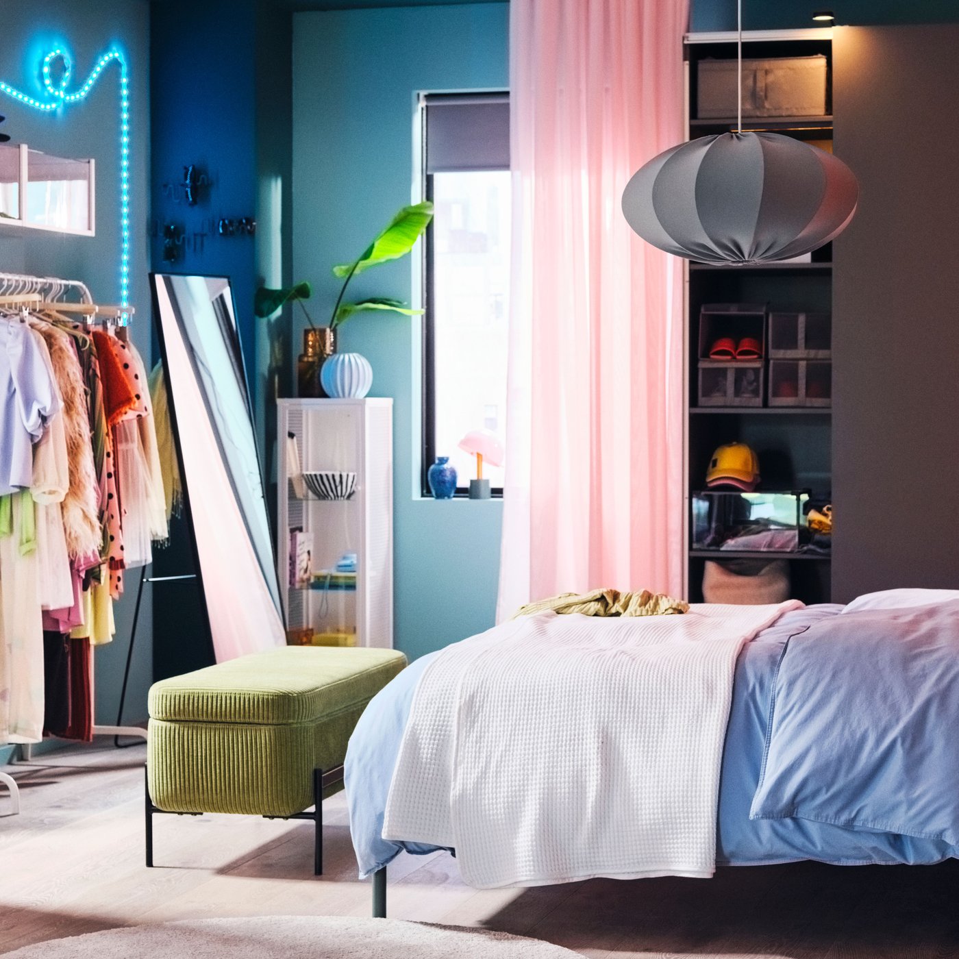 A vibrant bedroom with a TÄLLÅSEN upholstered bed covered in blue-grey ÄNGSLILJA bed linen in front of a PAX/HASVIK wardrobe.