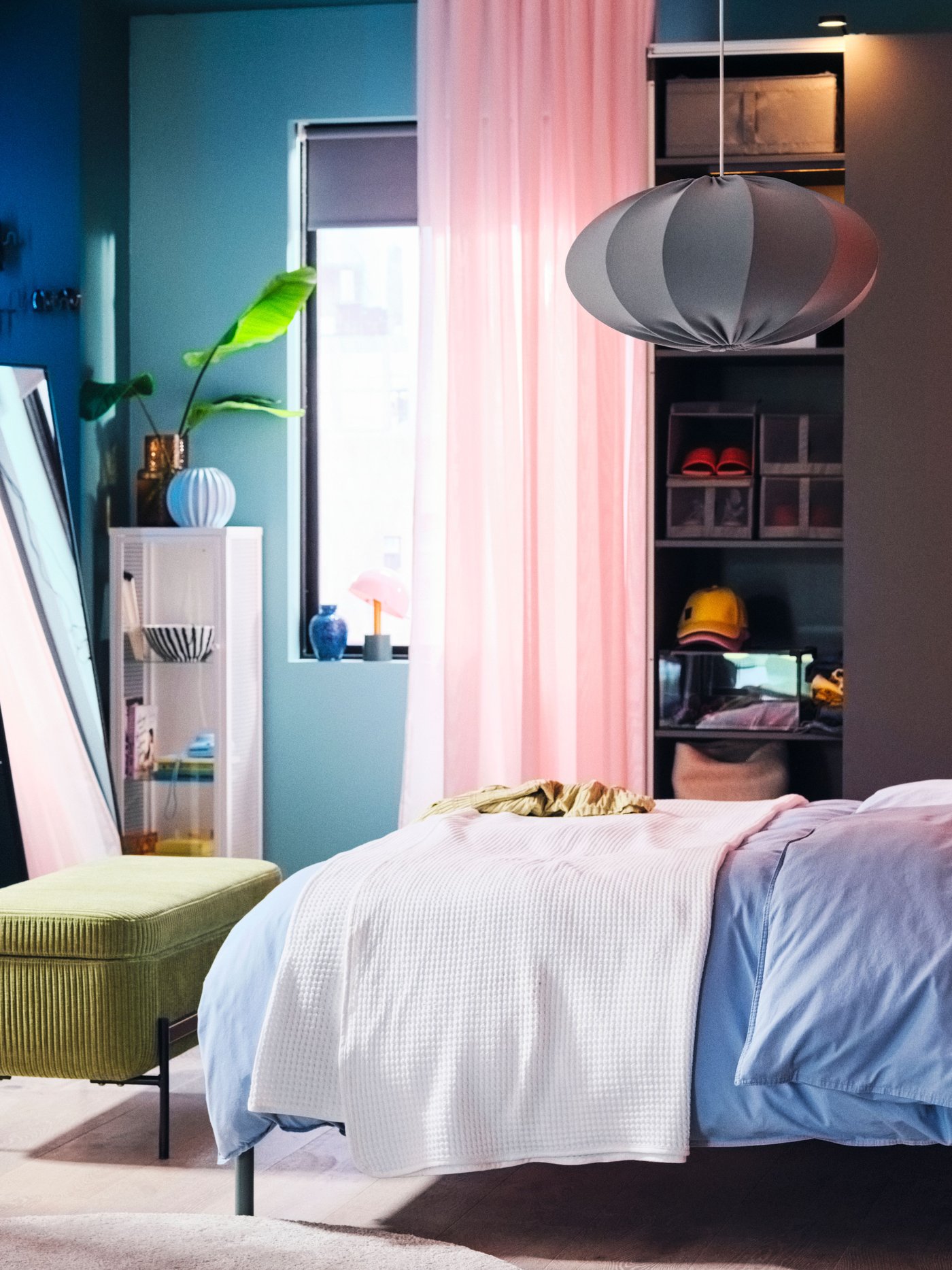 A vibrant bedroom with a TÄLLÅSEN upholstered bed covered in blue-grey ÄNGSLILJA bed linen in front of a PAX/HASVIK wardrobe.