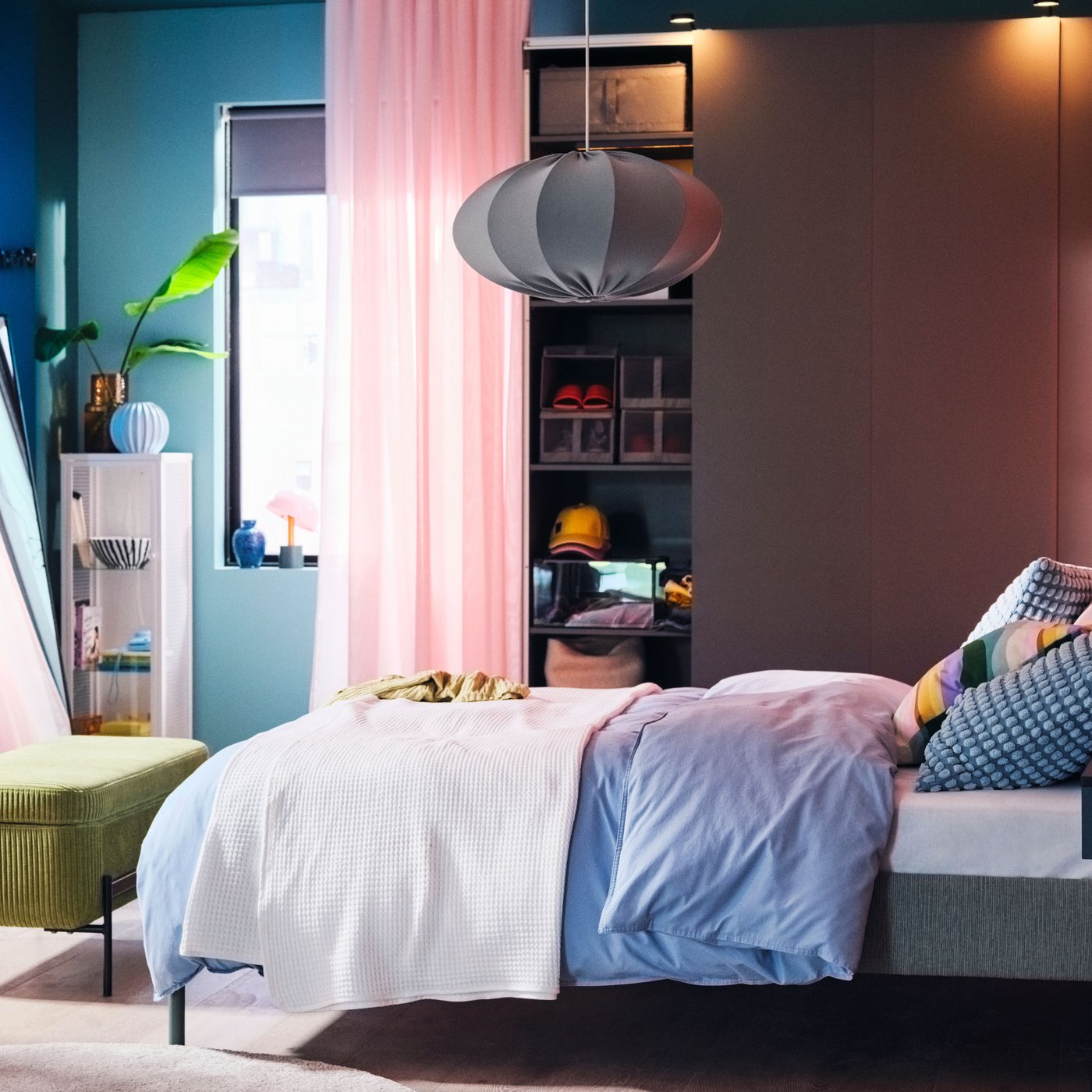 A vibrant bedroom with a TÄLLÅSEN upholstered bed covered in blue-grey ÄNGSLILJA bed linen in front of a PAX/HASVIK wardrobe.