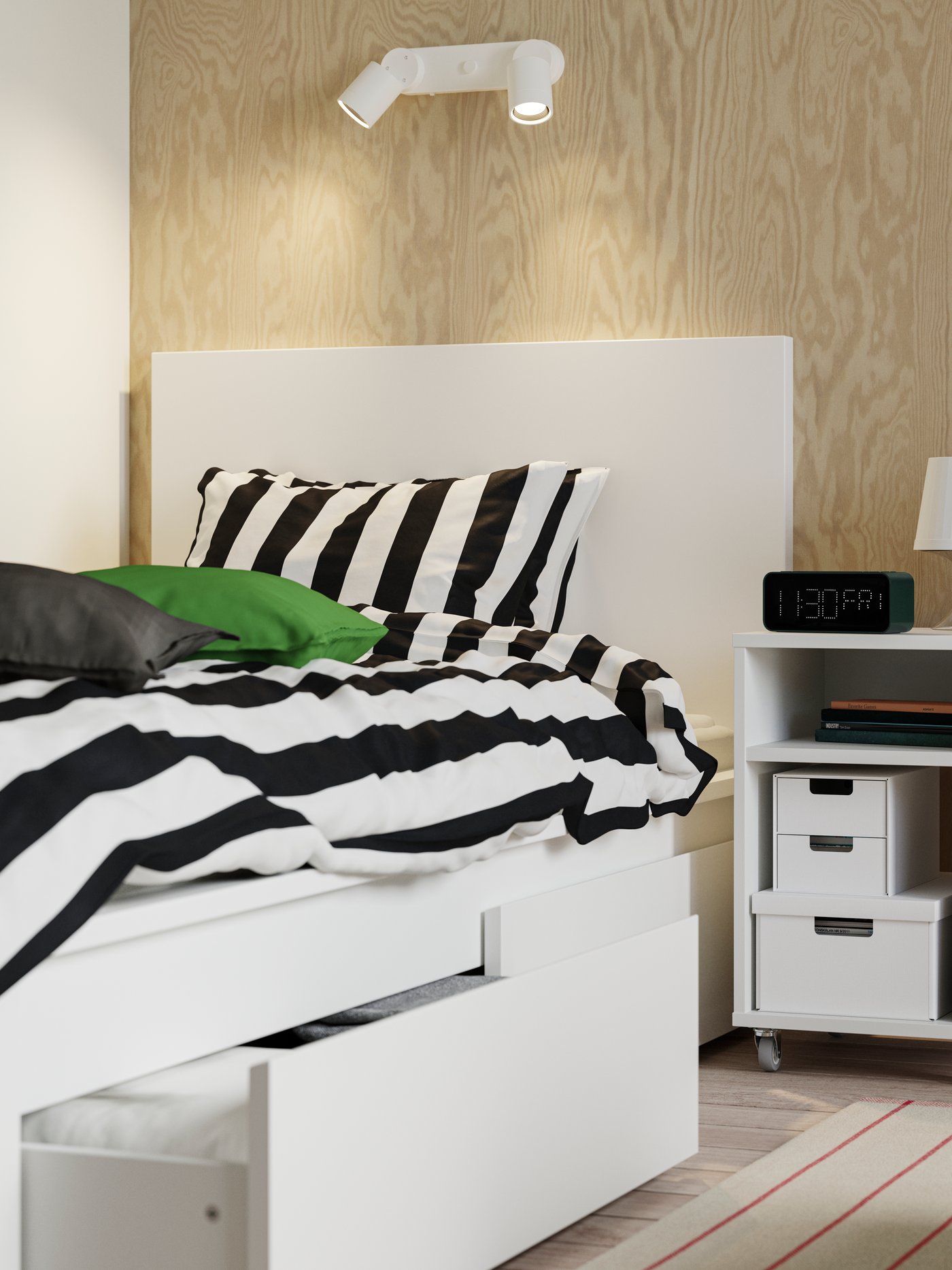 A white MALM bed frame with two storage boxes, one opened with textiles. On top is a SLÅNHÖSTMAL duvet cover.
