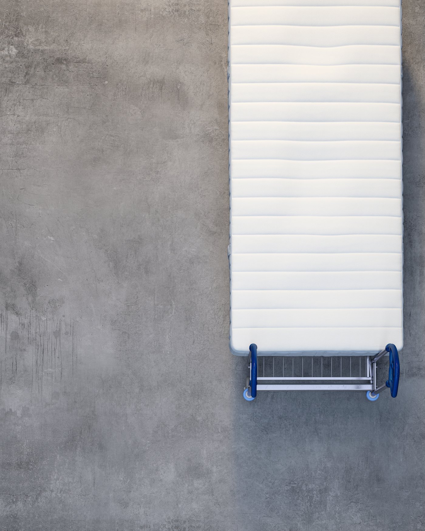 Set ovenfra og ned af en madras på en vogn på et betongulv.