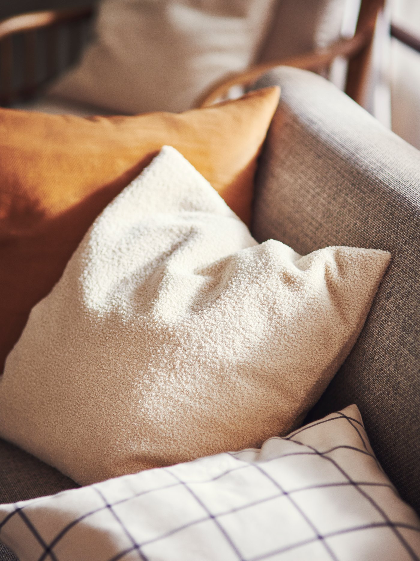 KRYDDBUSKE, VIGDIS and SPIKKLUBBA cushion covers are on a sofa. They are beige, dark golden-brown and white and black print.