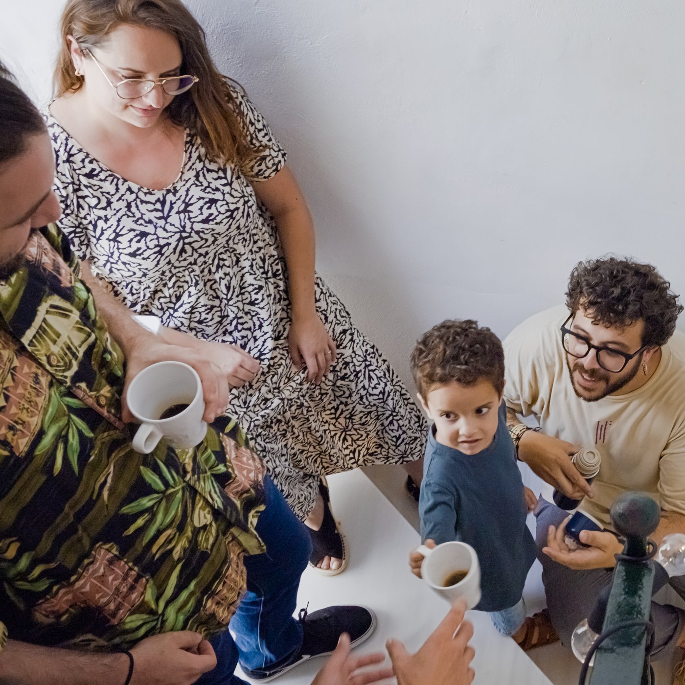 A group of neighbours are having coffee in FÄRGRIK mugs, in the staircase of an apartment building.