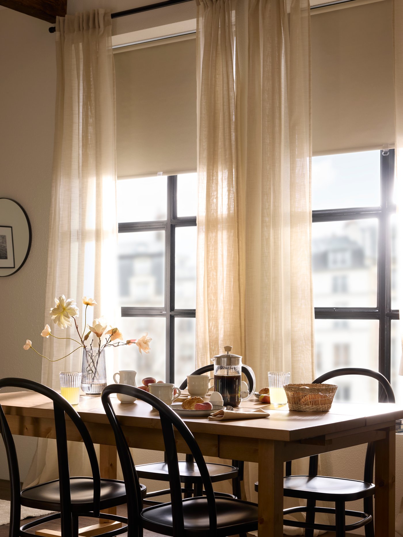 Śniadanie serwowane przy stole, a poranne światło wpada do pokoju przez dwa duże okna z tyłu.