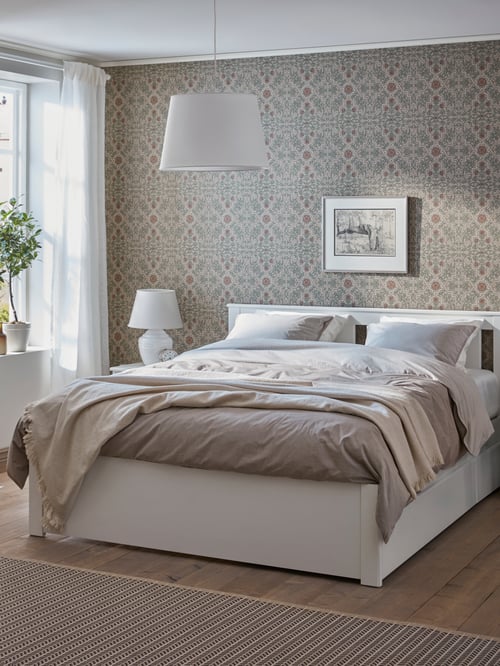 A white SONGESAND bed frame with four storage boxes has grey quilt covers and a white throw in a bedroom with a beige rug.