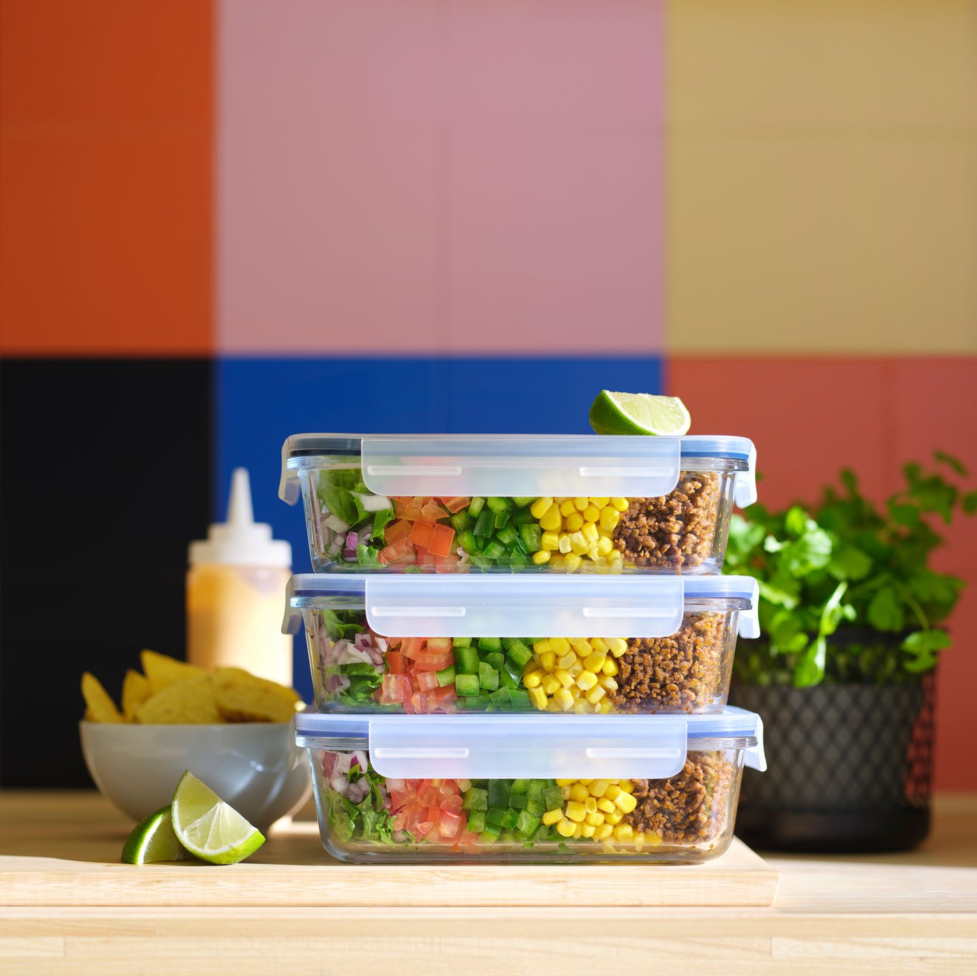 Three IKEA 365+ food containers with lid on top of each other, containing food, and an IKEA 365+ bowl holding potato chips.