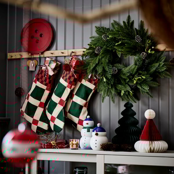 Three VINTERFINT Christmas stockings are hanging on racks with knobs above a sideboard with festive decorations.