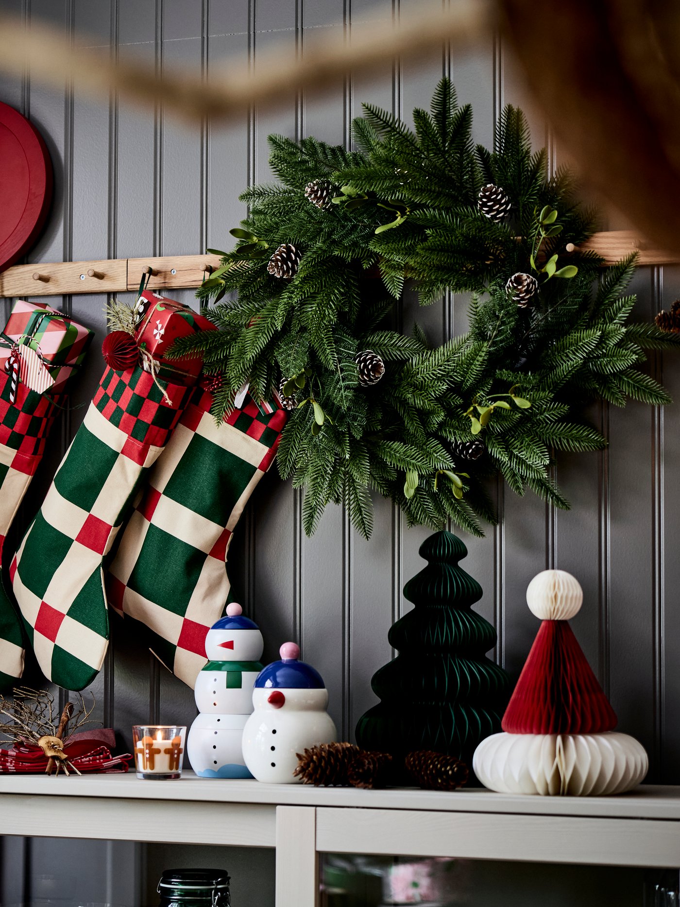 Three VINTERFINT Christmas stockings are hanging on racks with knobs above a sideboard with festive decorations.