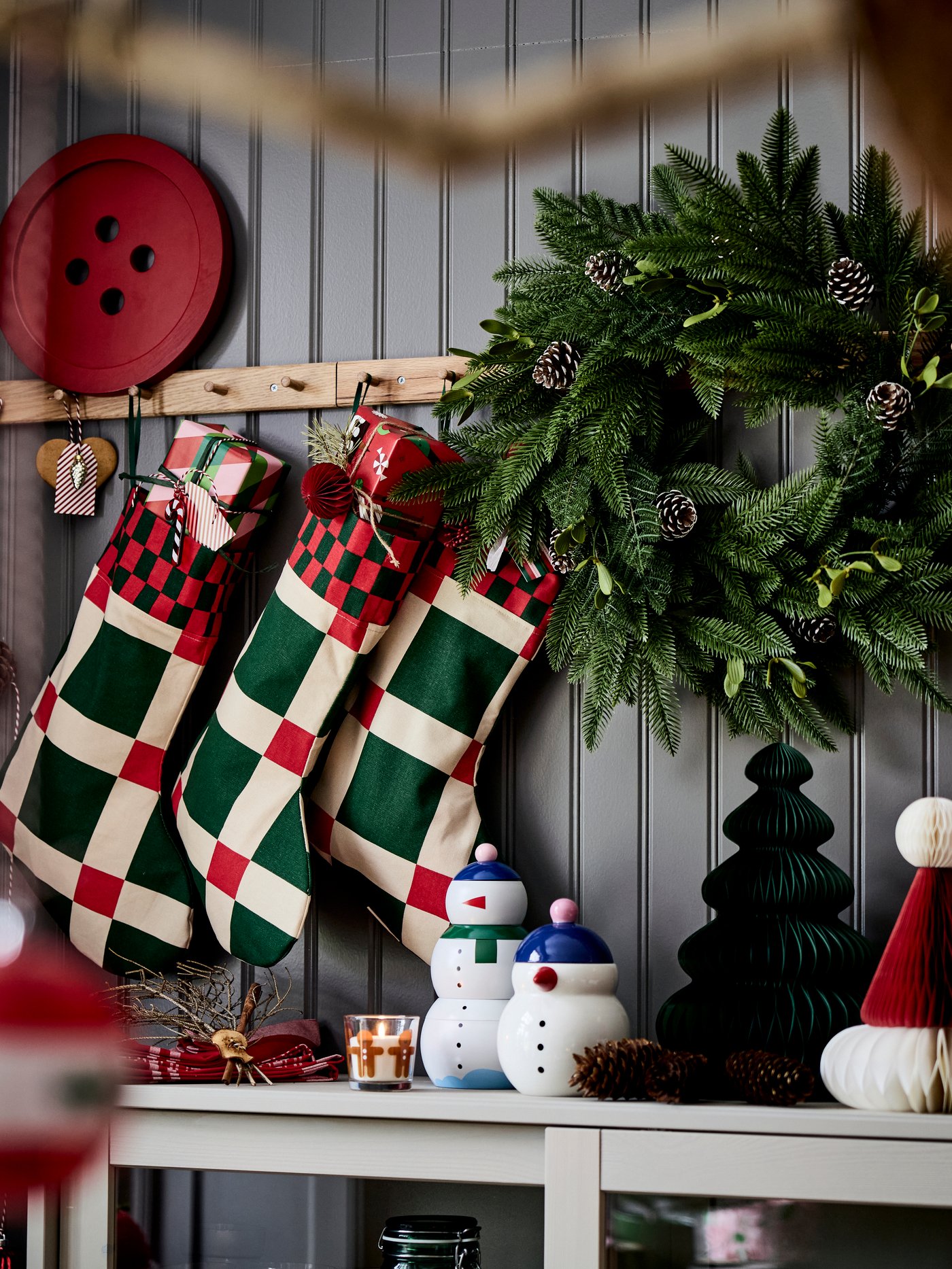 Three VINTERFINT Christmas stockings hanging on racks with knobs above a sideboard with festive decorations.