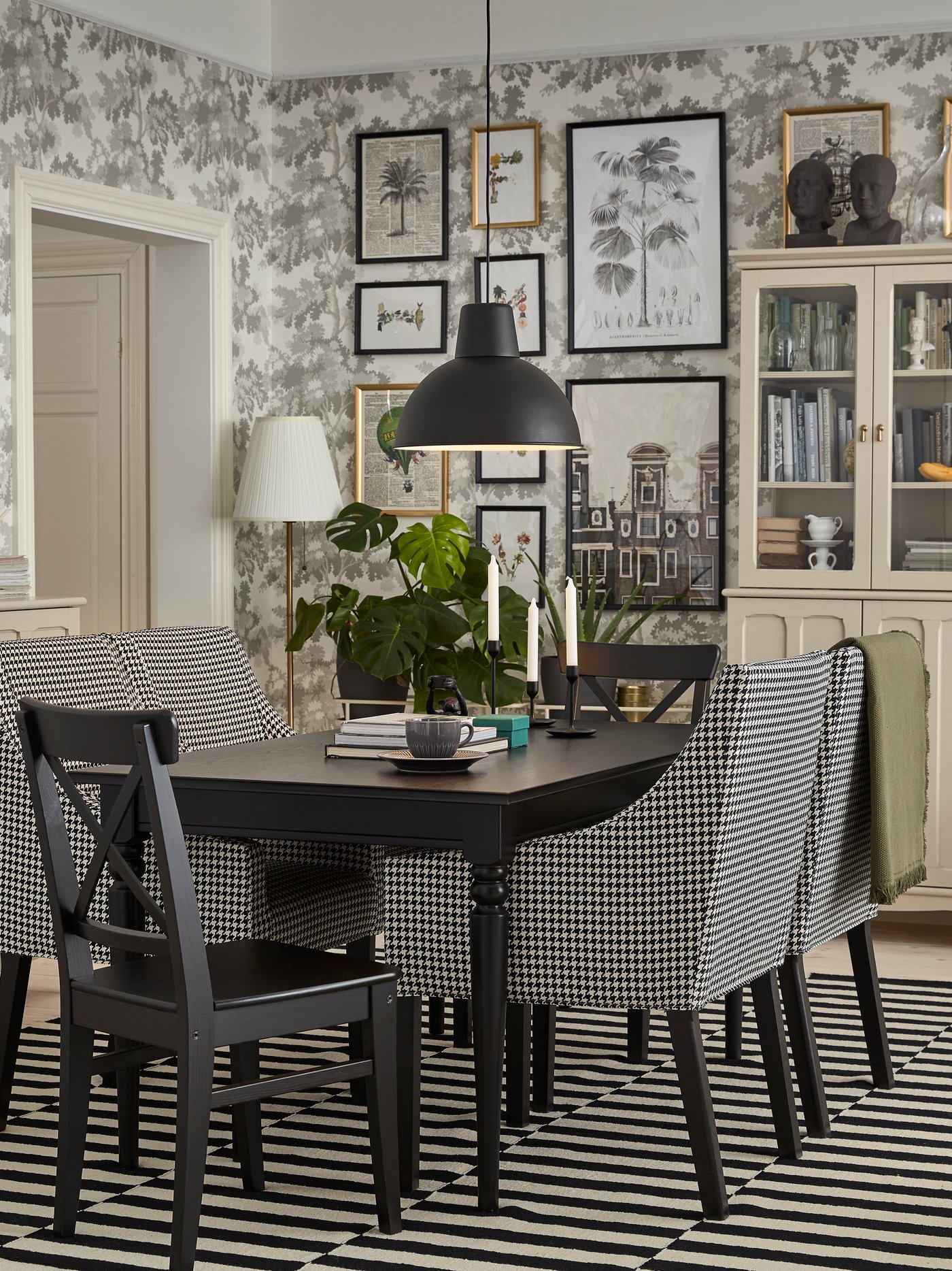 Comedor con mesa rectangular extensible de madera maciza, colocada sobre una alfombra de rayas, rodeada de múltiples sillas.