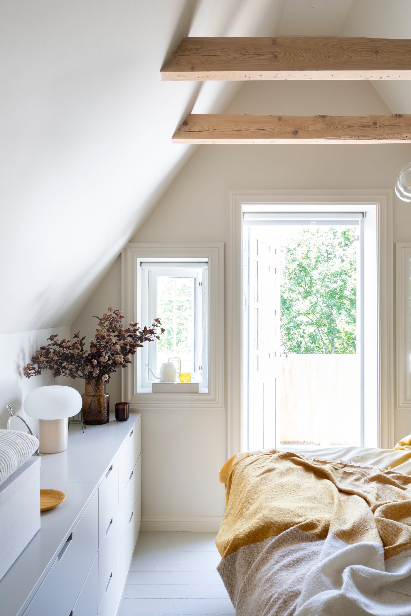 A light bedroom with a DEJSA table lamp, a KONSTFULL vase and a white NORDLI chest of drawers.
