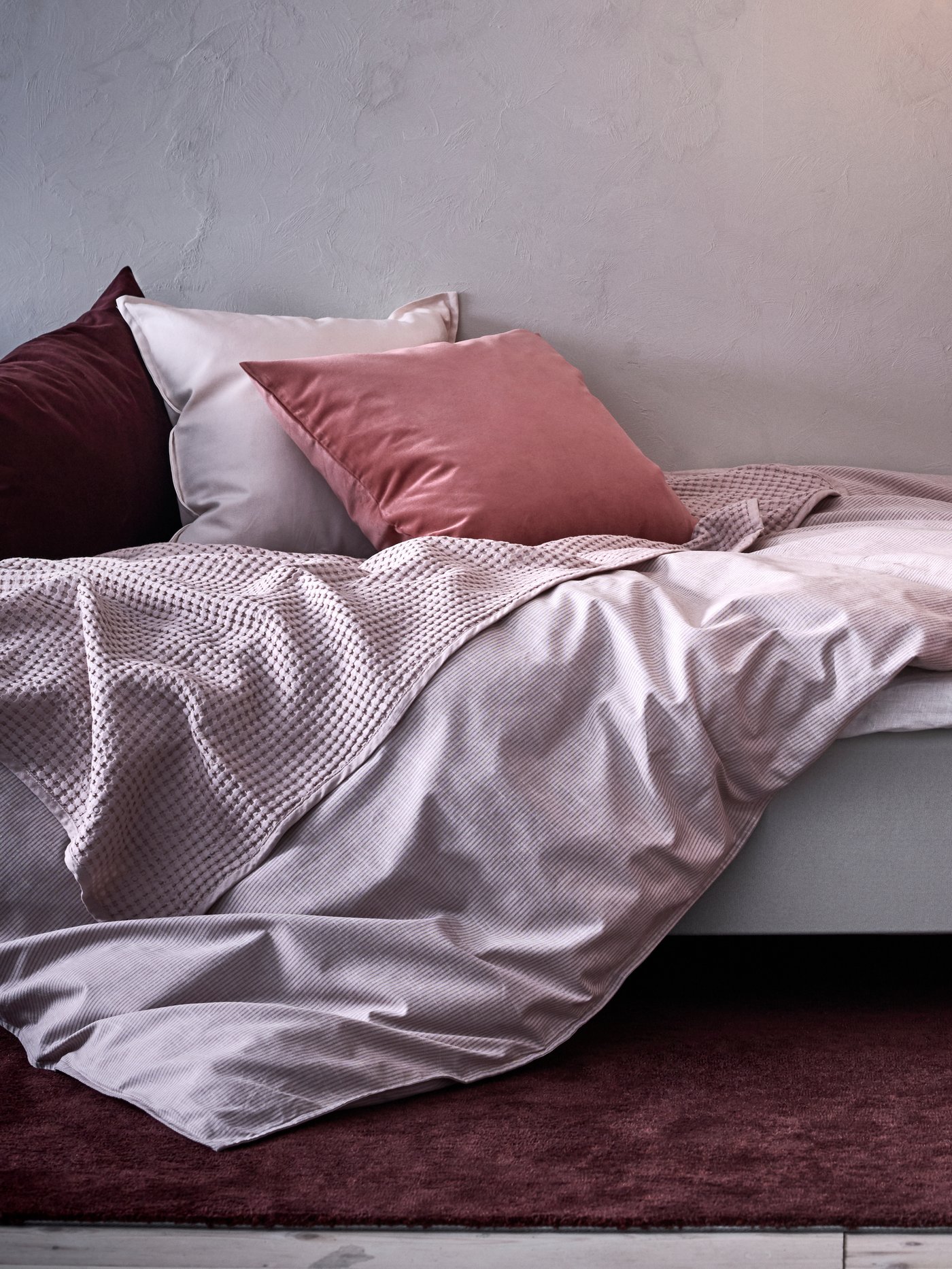 Un couvre-lit rose pâle de VÅRELD dans la chambre à coucher