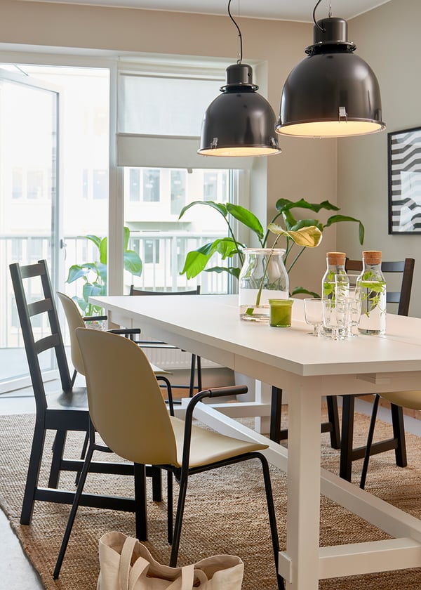 Vitt köksbord med svarta stolar och taklampor i industristil