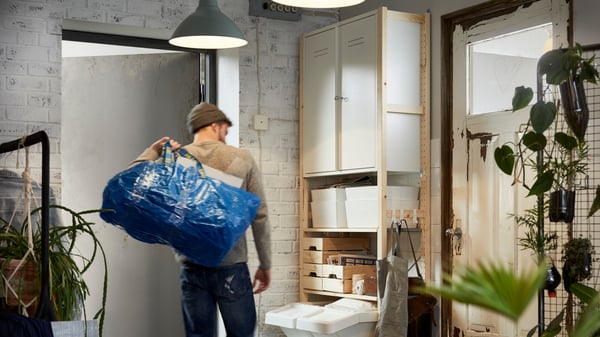 Két nevető nő sétál be egy IKEA áruházba sárga IKEA táskákkal, az egyik egy lépéssel a másik előtt jár.