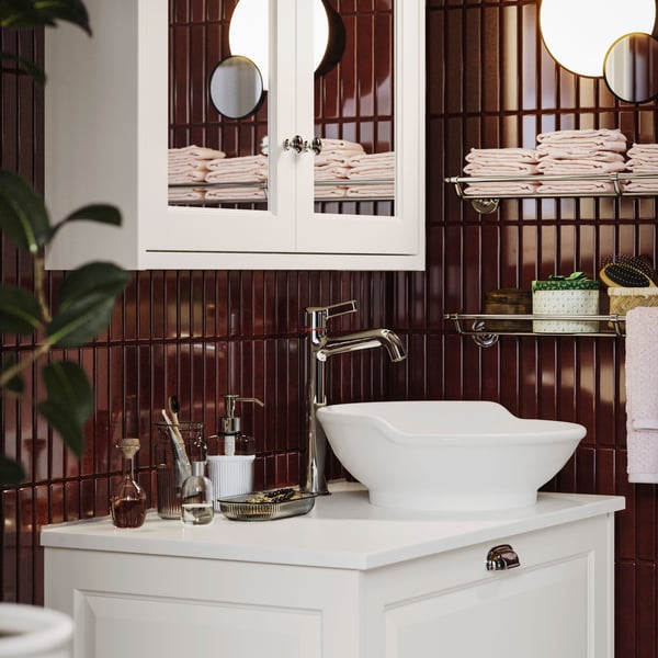 Modern bathroom with VOXNAN wash-basin mixer tap and white vanity unit, featuring dark red tiles and a mirrored cabinet.