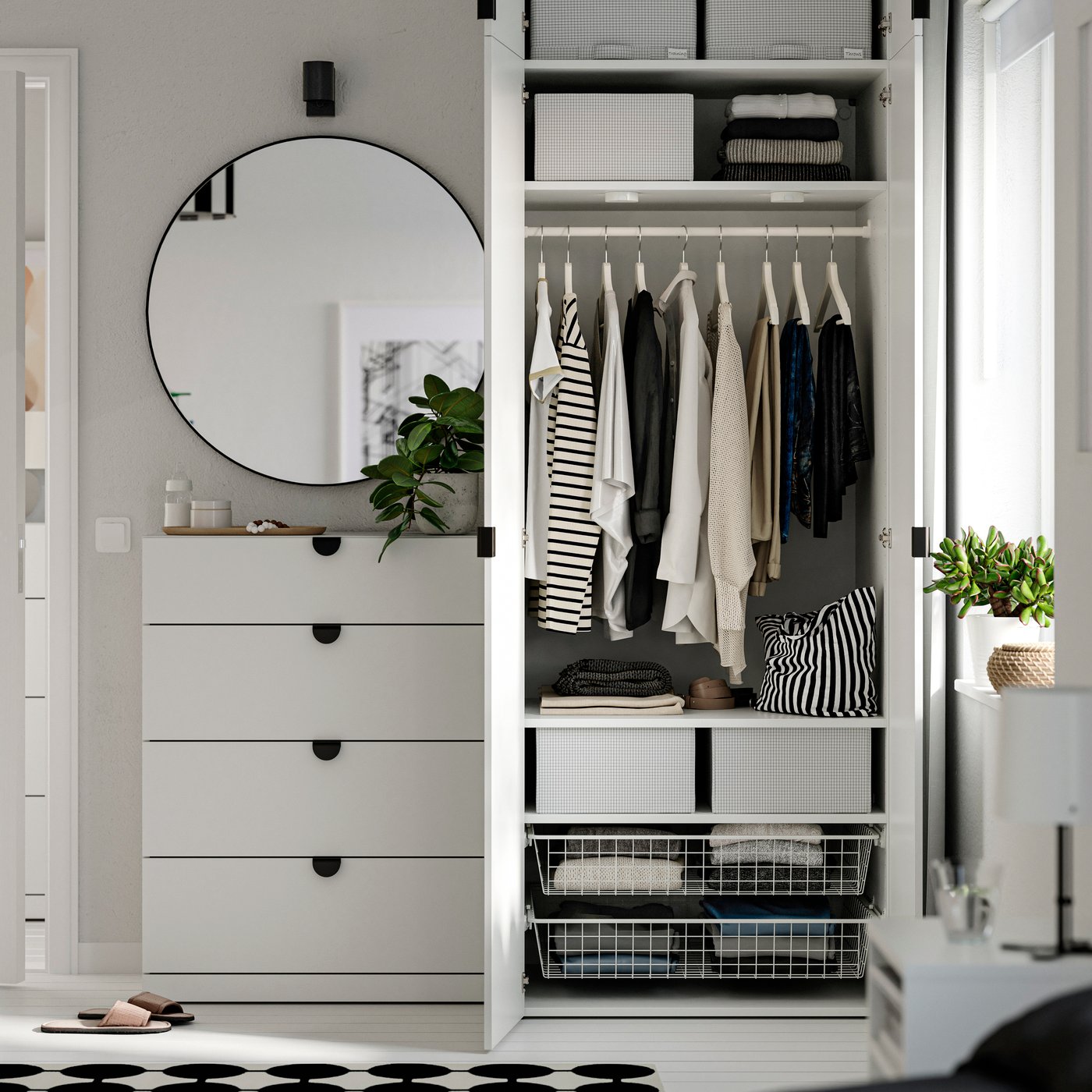 Ein Schlafzimmer mit einer weißen LASTARE Schrankkombination mit Böden und hängender Kleidung neben einem runden Spiegel.