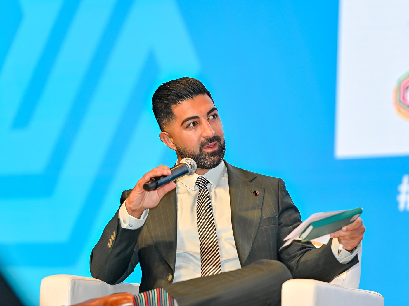 Arash speaking into a microphone on stage at a UNHCR event.