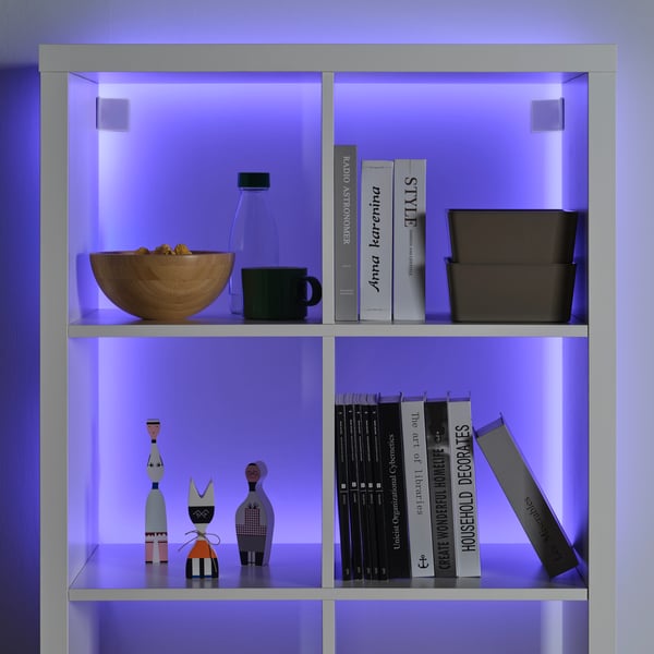 A white KALLAX shelving unit in the living room with a purple-lit KABBLEKA LED lighting strip.