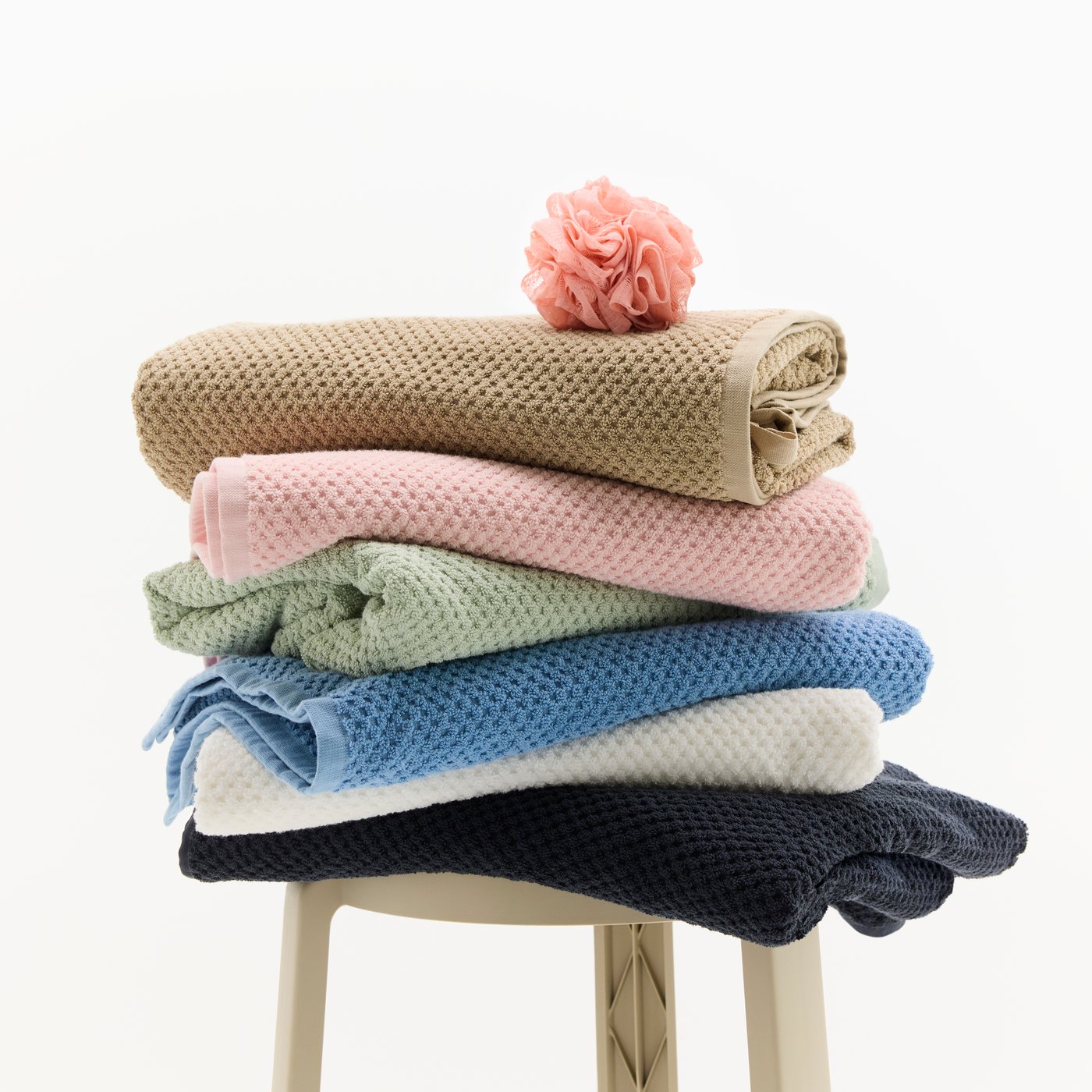 Nahaufnahme von sechs gefalteten GULVIAL Handtüchern in den Farben Beige, Rosa, Grün, Blau, Weiss und Schwarz.