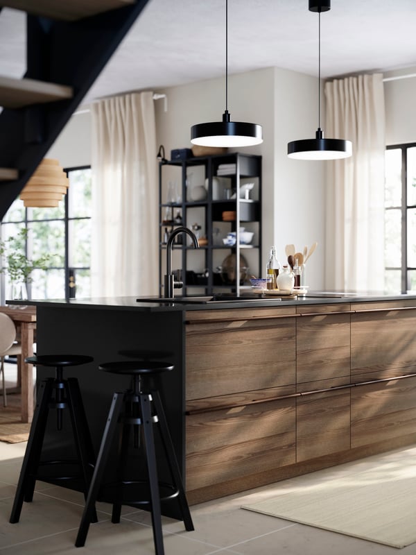 Kitchen with STENSTA dark brown ash veneer drawer fronts, black countertop, black tap, and shelves filled with kitchenware.