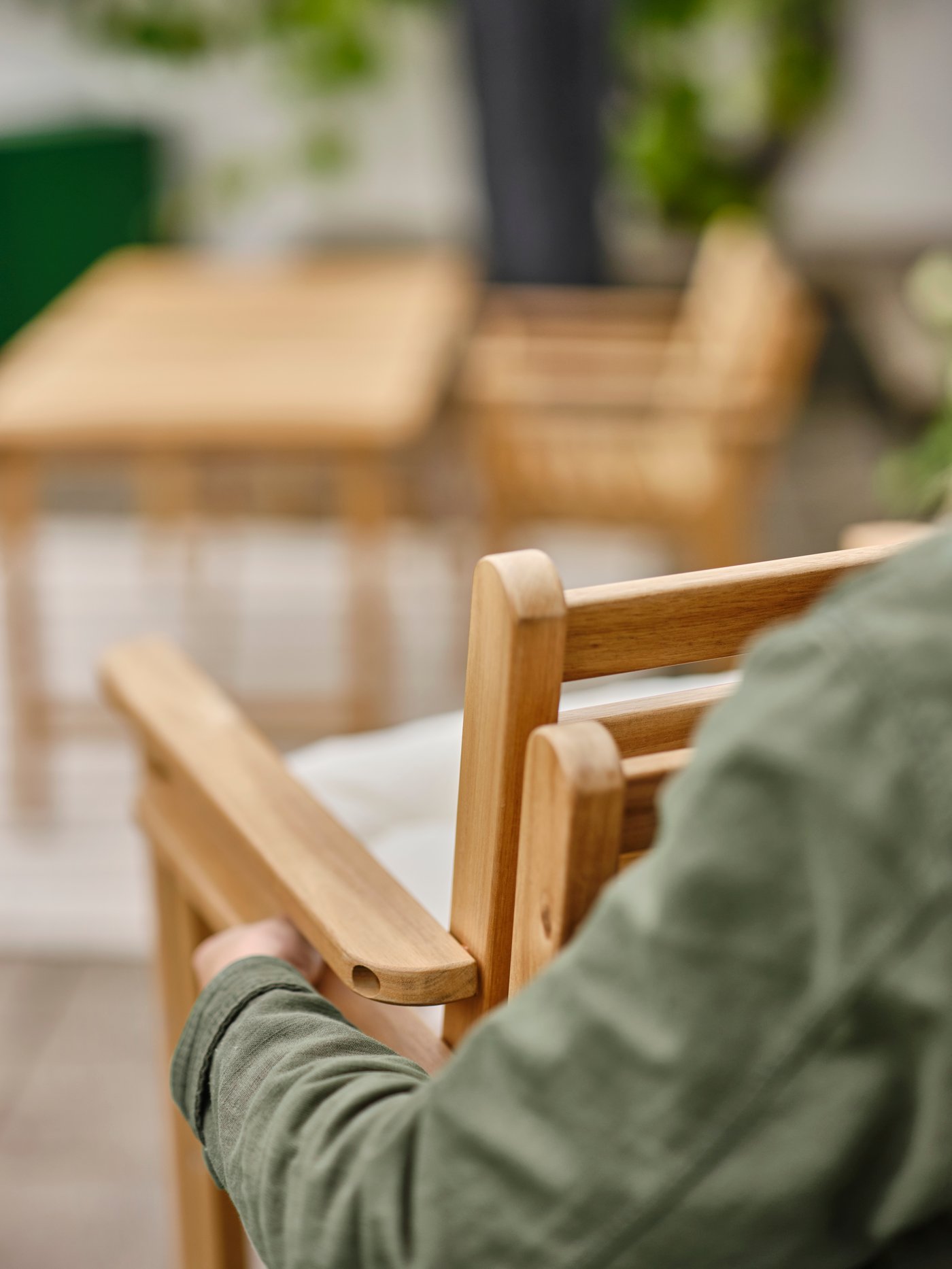 Člověk nesoucí dvě nastohované židle ASKHOLMEN s područkami. V pozadí je vidět stůl.