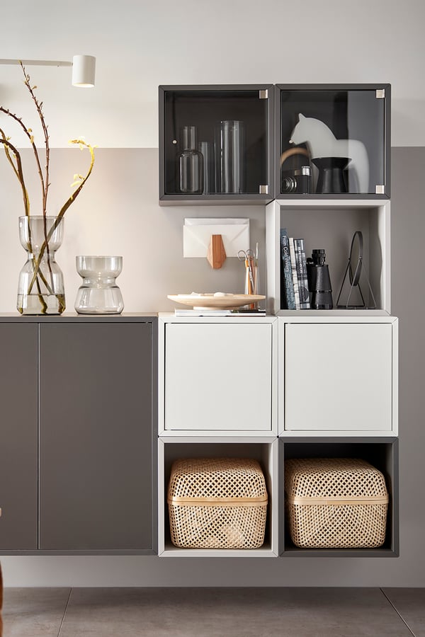 Estante de almacenamiento con diferentes coompartimientos con puertas, cajas organizadoras y cosas a la vista.