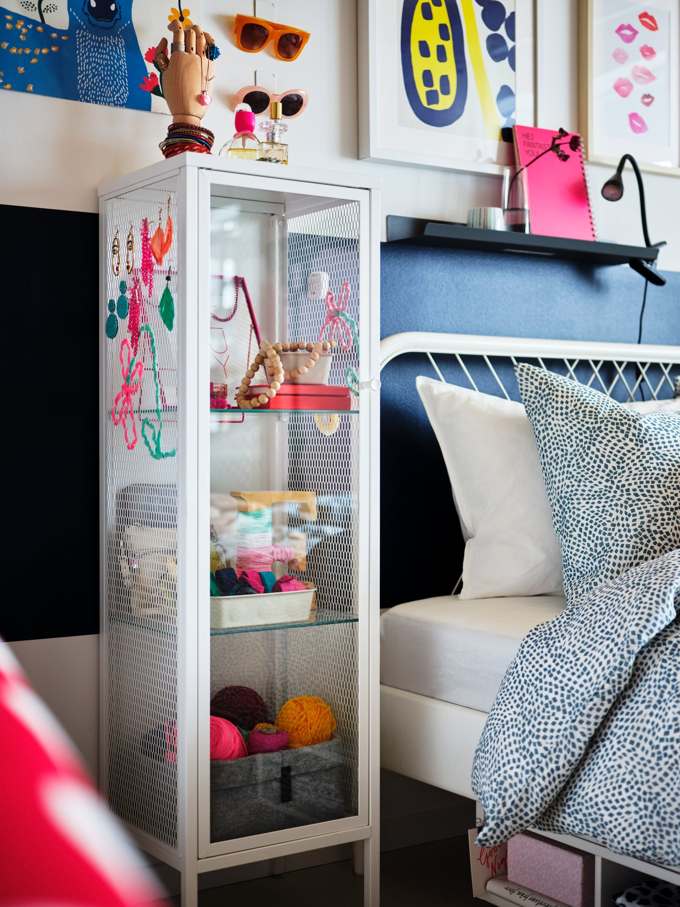 Et vitrineskab står er fyldt med nips, står ved siden af en seng. 