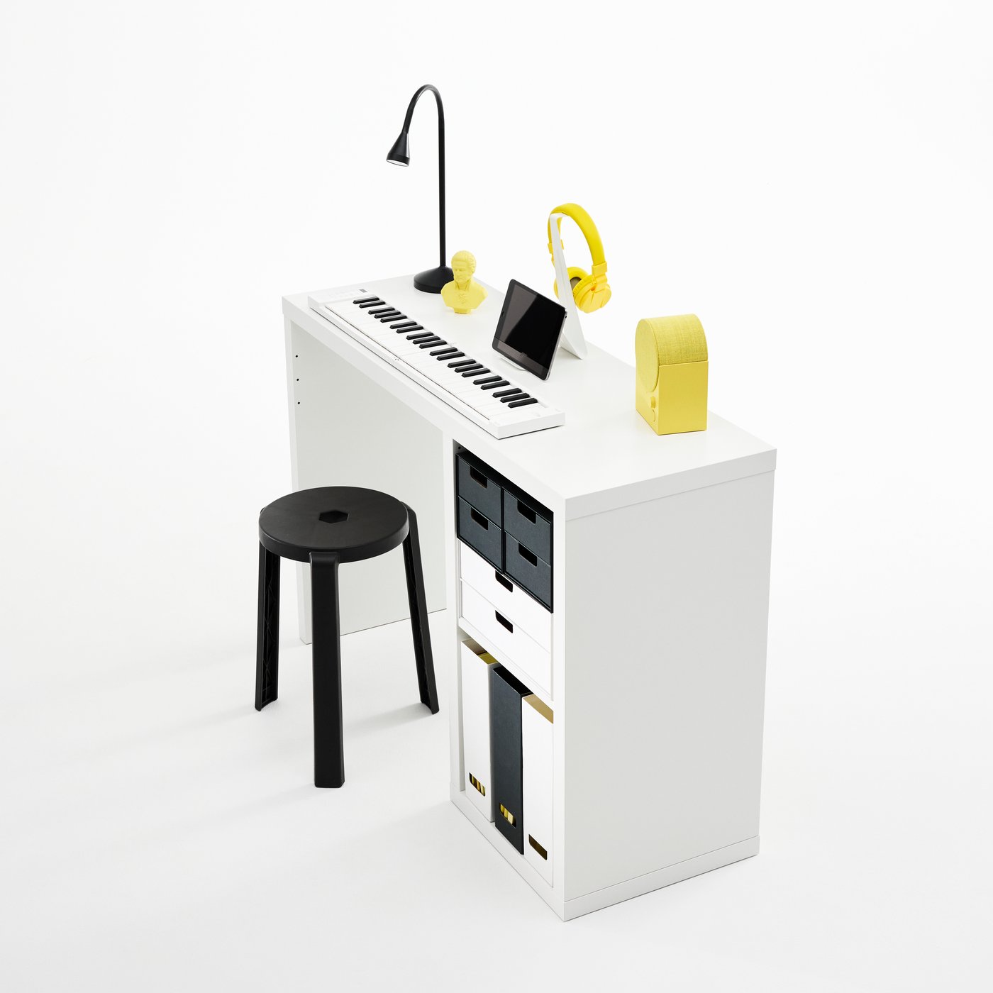 A slim, white KALLAX desk featuring neatly arranged keyboards, tablet, headphones and table lamp. Inserts and organisers.