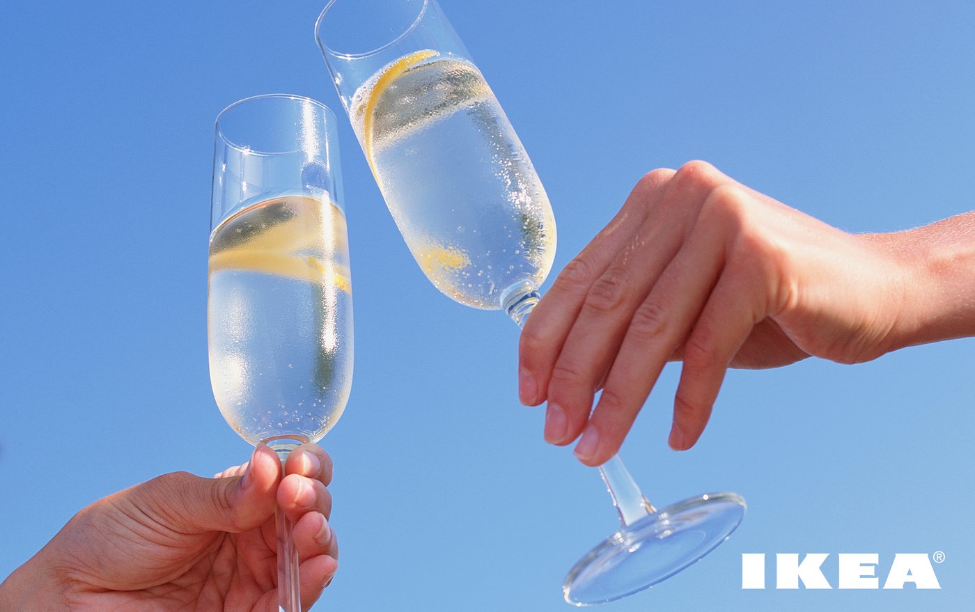 Närbild på en skål med två champagneglas mot blå himmel.