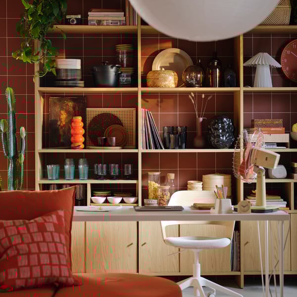 A LÅDMAKARE shelving unit with cabinet doors in a deep red living room, with turquoise VARDAGEN glasses placed on its shelf.