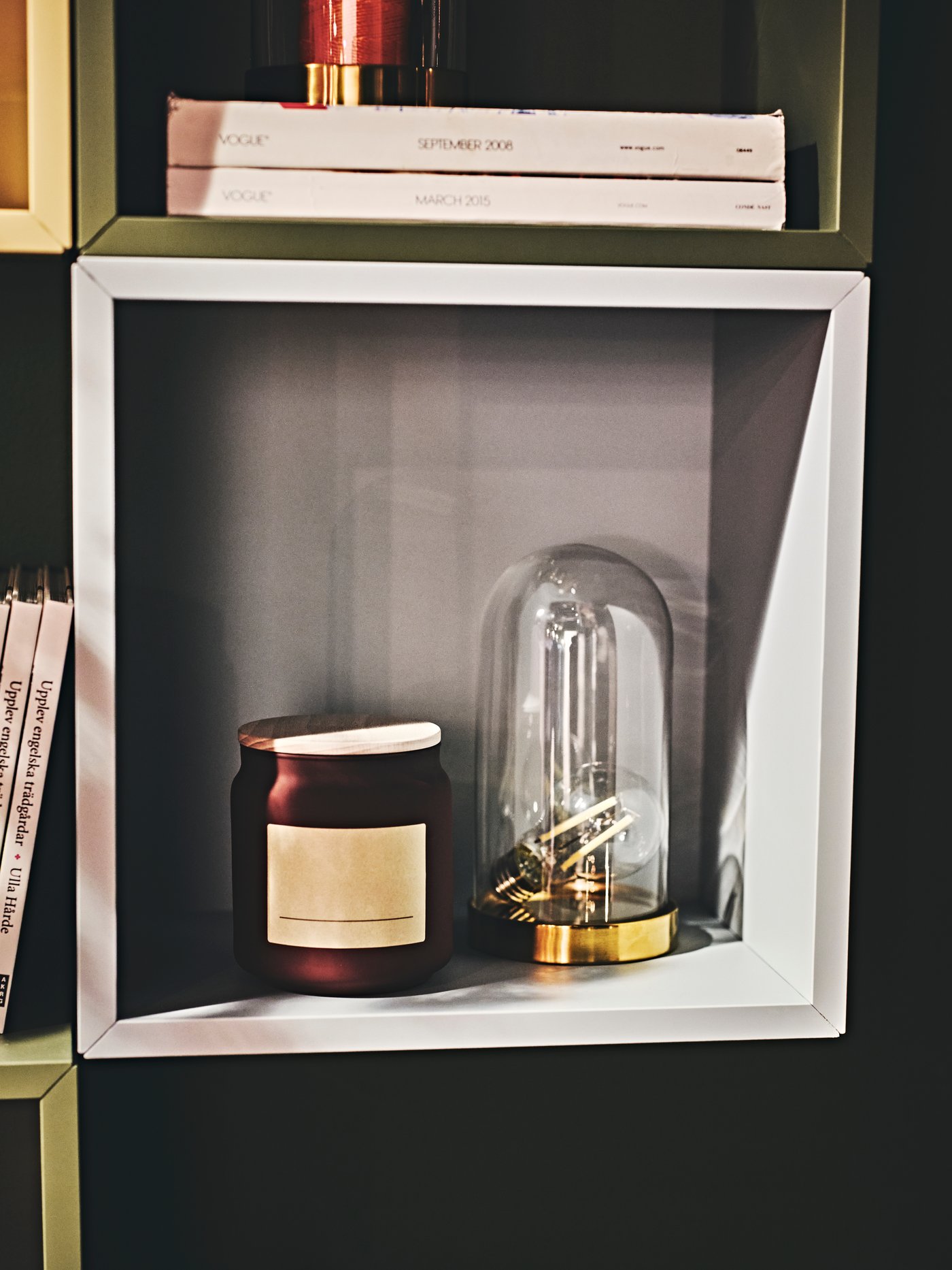 Otevřená police EKET v světle zeleno-modré barvé s dekorací a dózou uvnitř.