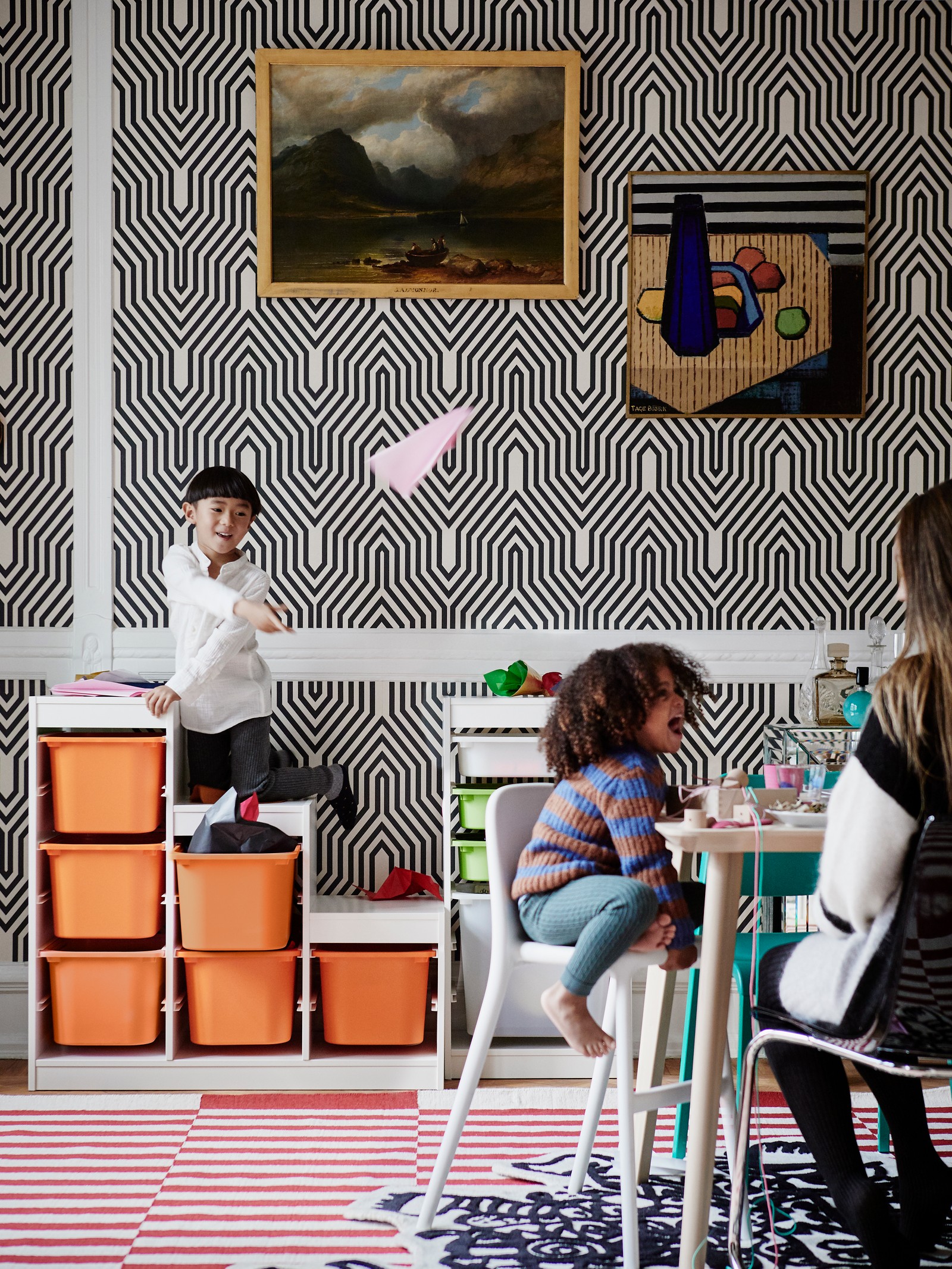 Deca se igraju u prostoriji u kojoj se vie kutije za odlaganje narandžastih nijansi.