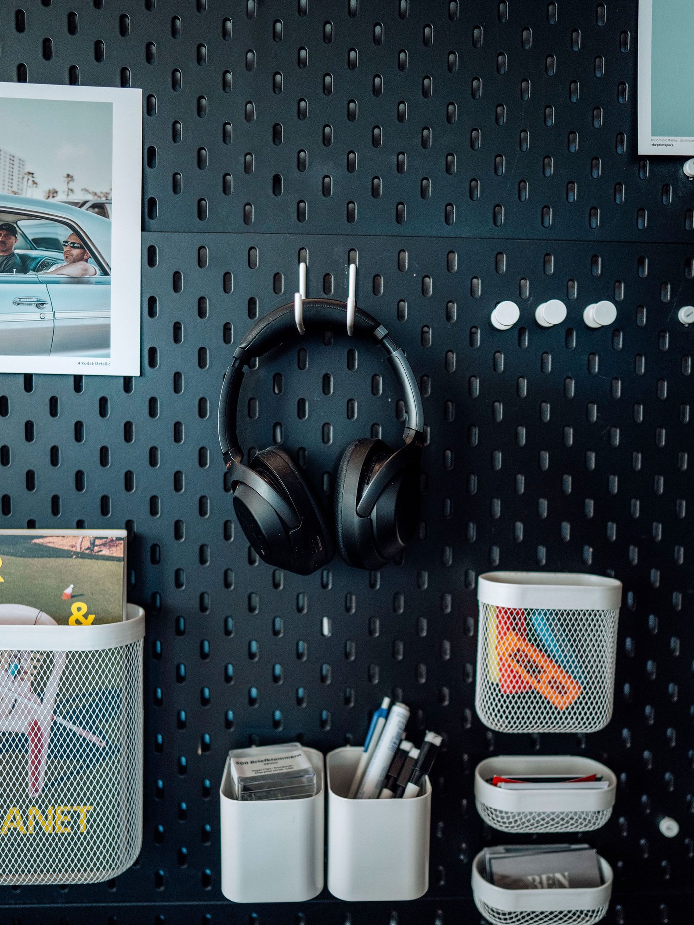 Svart SKÅDIS förvaringstavla med vita krokar och förvaringslådor.