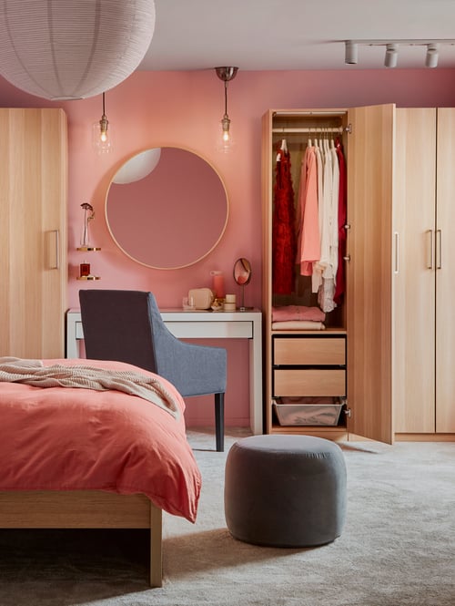 A modern bedroom has a white MALM dressing table as a vanity area in between wardrobes with white stained oak effect doors.