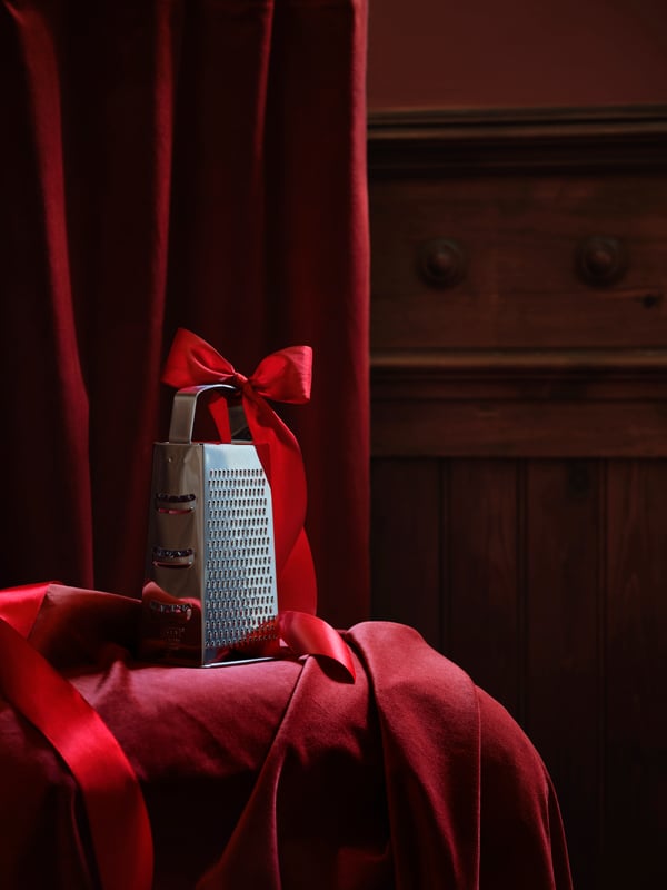 A stainless steel IDEALISK grater in the kitchen on a red velvet background.