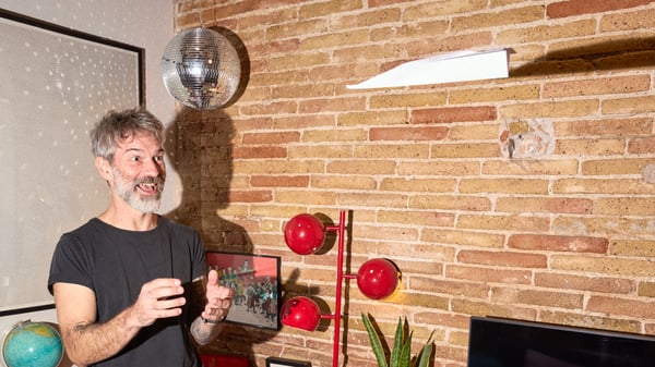 A man is very joyful and playful inside his home with a paperplan coming towards him and a discobowl hanigng from the roof. 