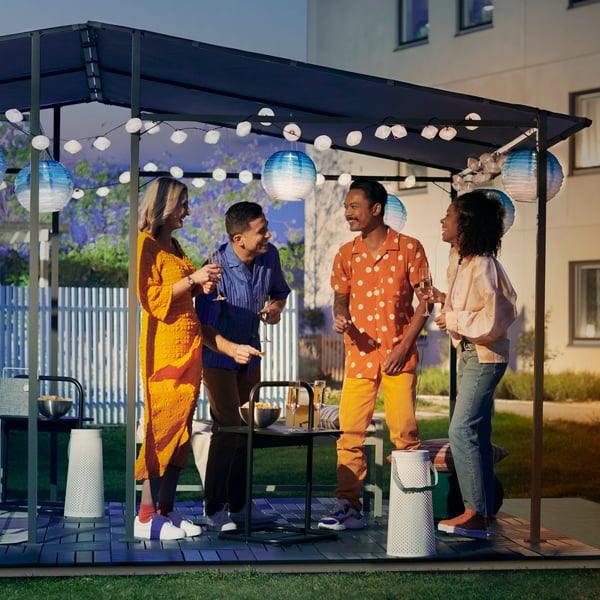 Volwassenen gekleed in oranje staan onder een GUNNÖN partytent en hebben lol met elkaar.