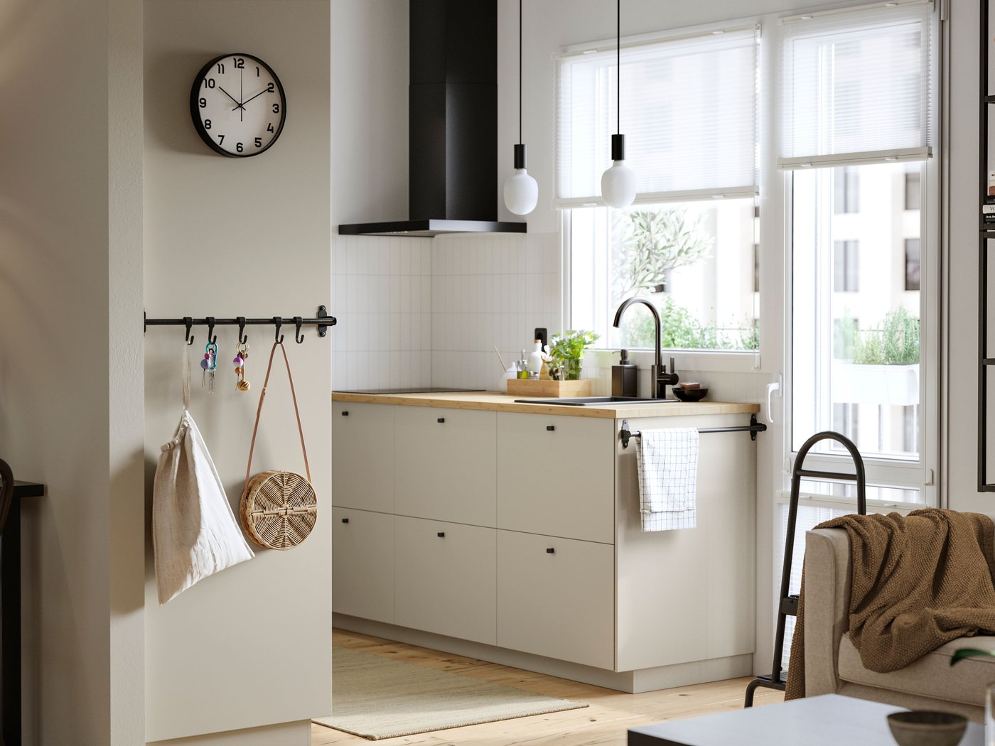 A kitchen with a window and a balcony door has beige HAVSTORP fronts and a MATÄLSKARE wall mounted extractor hood in black.