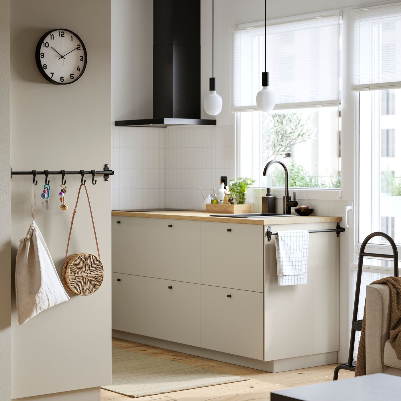 A kitchen with a window and a balcony door has beige HAVSTORP fronts and a MATÄLSKARE wall mounted extractor hood in black.