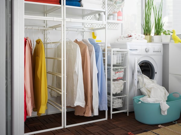 Planificador JONAXEL de logia, camisas de diferentes colores colgadas en su interior, a su lado una lavadora y un carro organizador. 