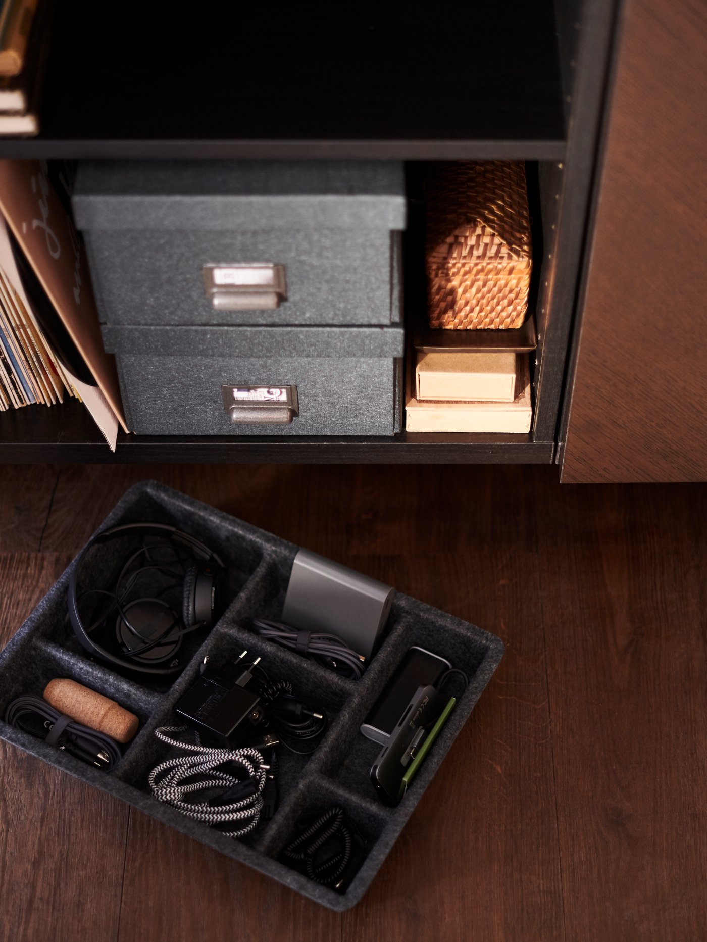 שני מדפים בארון פתוח עם קופסאות על המדף התחתון. על הרצפה בחזית מונח מגש RAGGISAR, שבו פריטים קטנים.