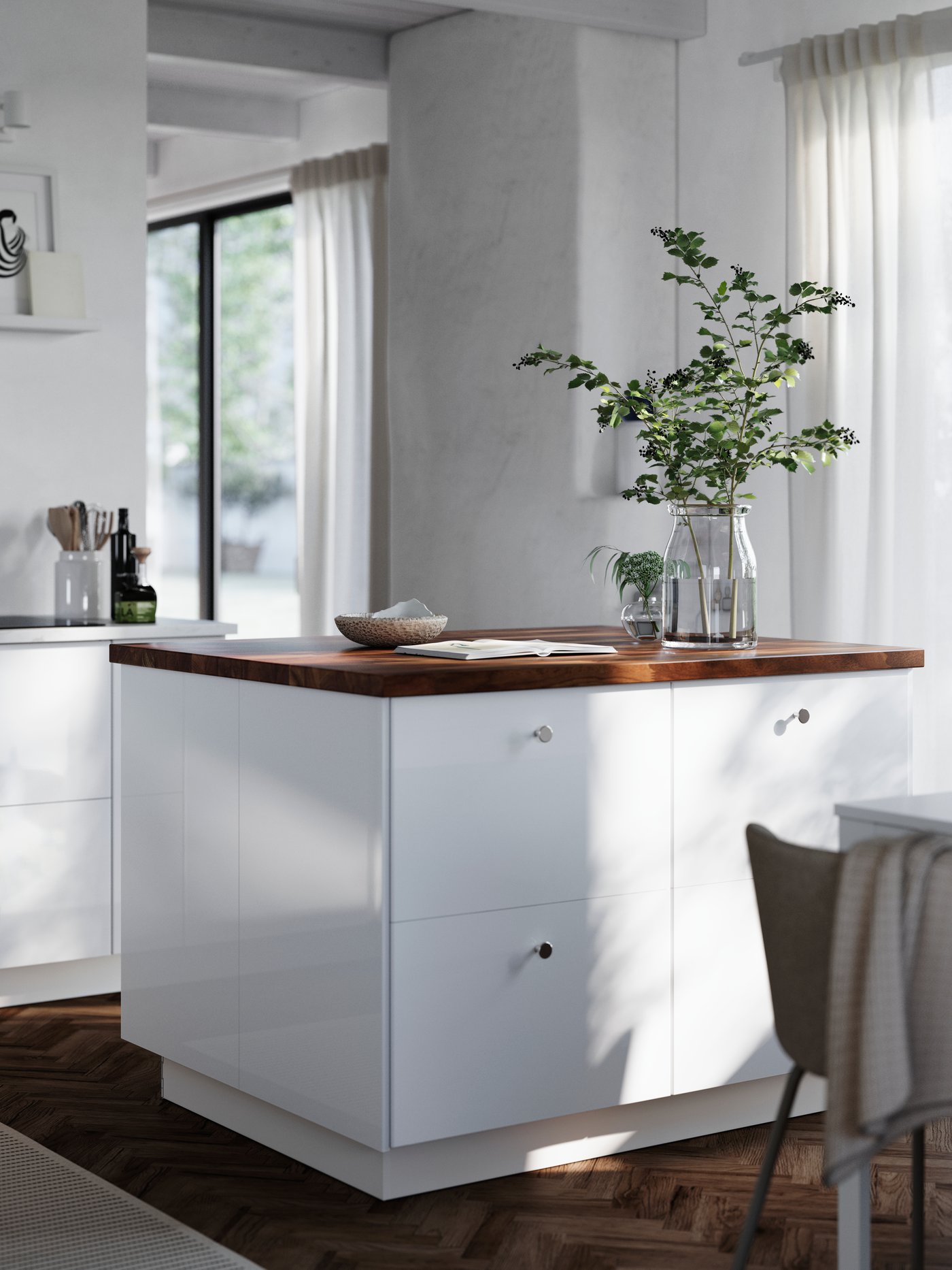 A white kitchen island with a worktop and cover panels in dark walnut look stands in a kitchen with RINGHULT fronts.
