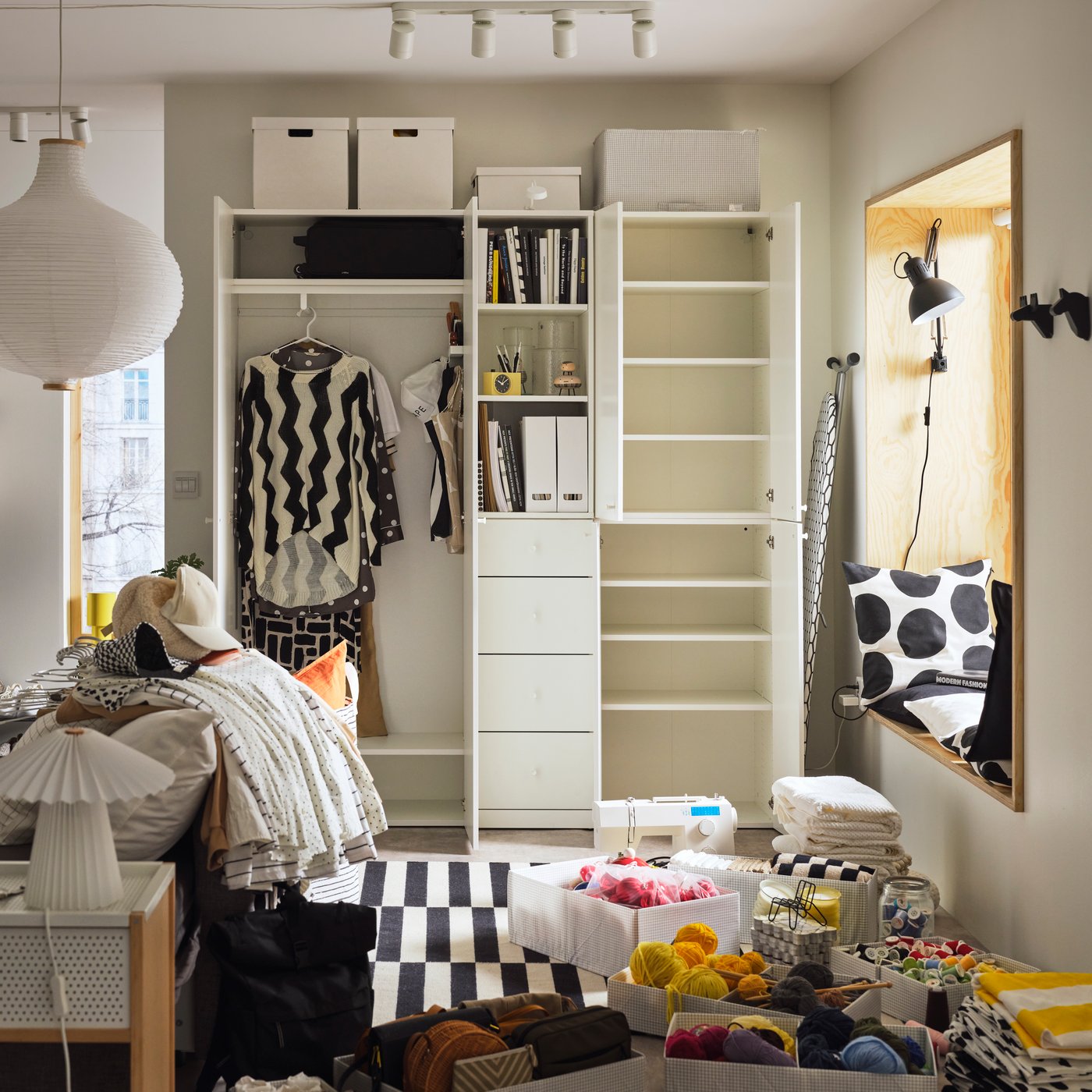 A LASTARE wardrobe combination with shelves and storage boxes in a bedroom with yarn, textiles and containers on the floor.