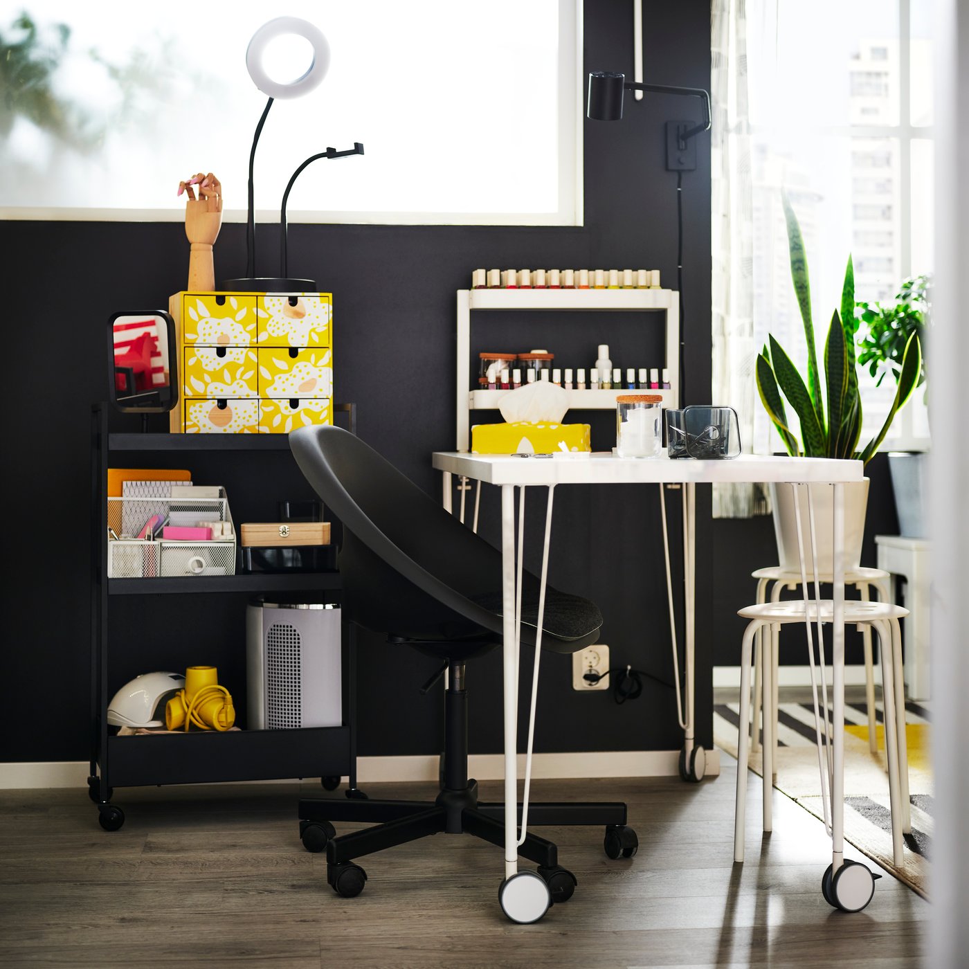 A white LAGKAPTEN/KRILLE desk sits beside a black ELDBERGET chair in a bright workspace filled with hobby materials.
